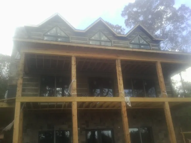 Dormers and porch framing on a large log home under construction — Roof Coating work by our crew in Cartersville
