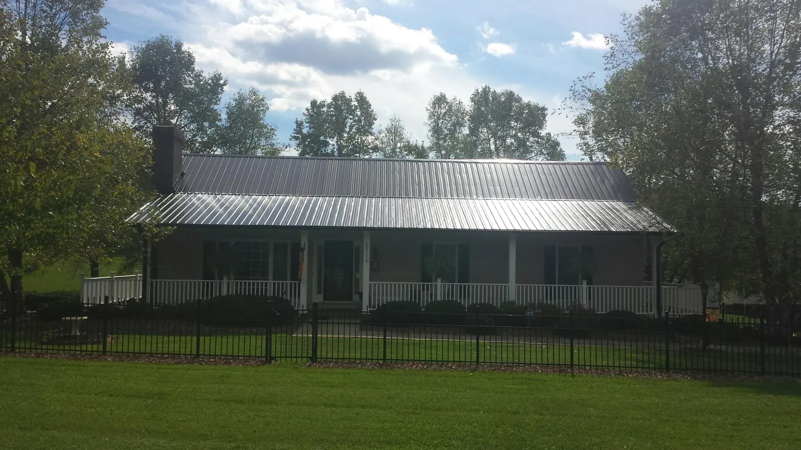 Gray metal roof on a brick ranch with a full width front porch — Gutter Guard Installation work by our crew in Cartersville